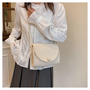 Detailed macro view of cream straw woven crossbody bag with large pearl buckle