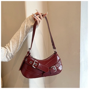 Detail of burgundy hobo bag with glossy leather texture and silver eyelet buckles