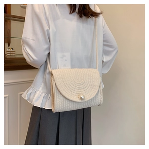 Detail view of woven straw crossbody bag featuring cream white texture and pearl buckle