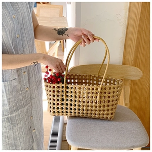 Close-up of beige woven hollow handbag with thin double handles and grid texture design