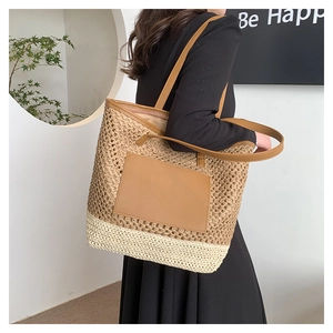 Close-up of two-tone hollow woven straw tote bag with brown leather patch detail