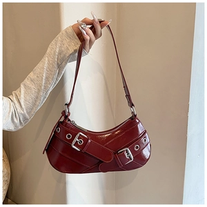 Detail shot of a burgundy faux leather shoulder bag with silver hardware and vintage buckles