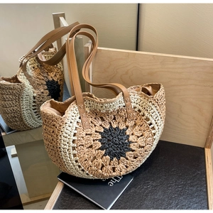 Detail of hand-woven sunflower straw tote bag with brown faux leather handles