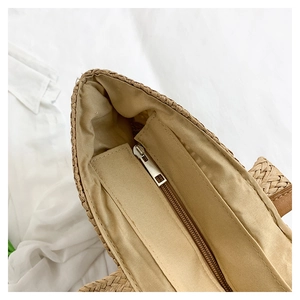 Detailed top view of large straw tote with fabric lining and secure zipper closure