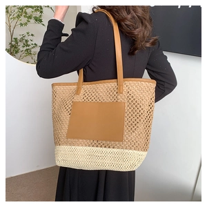 Detail of handwoven straw tote bag with dual-tone texture and brown leather strap