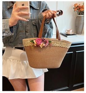 Detail of straw tote bag with white lace trim, floral accents and brown leather handles