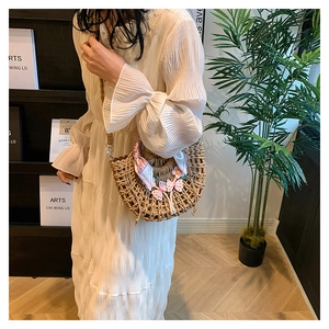 Detail of woven straw shoulder bag with floral bow accents and patterned silk scarf wrap