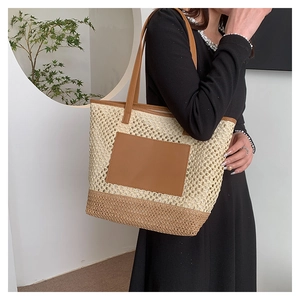 Detail of hand-woven straw beach bag with brown leather patch and shoulder straps