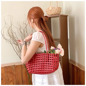 Detail of red hollow woven beach bag with diamond pattern and long handles