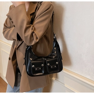 Detail of black motorcycle style hobo bag with silver rivets and dual front pockets