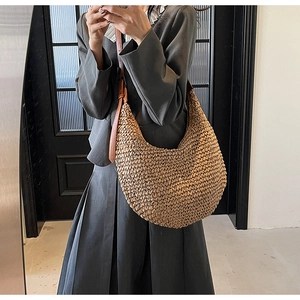 Detail of woven straw hobo bag with dark brown leather strap for summer beach fashion