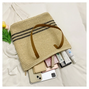 Detail of woven straw tote bag with black stripes and summer essentials on white cloth