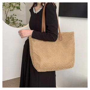 Detail of hollow-out straw weave texture and brown leather strap on large summer tote