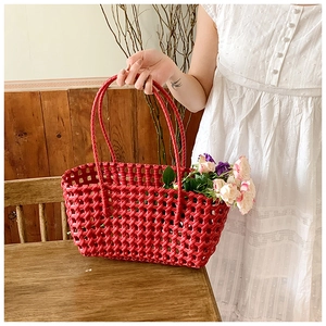 Detail of red hollow woven basket bag featuring elegant slim handles and large capacity