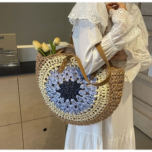Detailed close-up of woven straw handbag featuring colorful crochet floral embroidery pattern