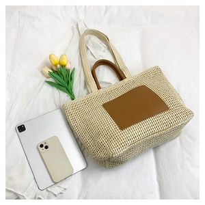 Macro detail of straw tote bag showing spacious interior with leather straps and texture