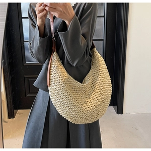 Close-up of woven straw texture and adjustable brown leather strap on hobo bag