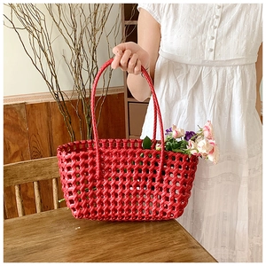 Detail of red hollow woven basket bag featuring durable mesh texture and sturdy double handles