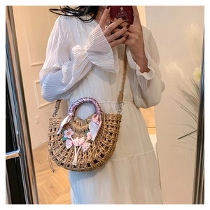 Detail of a semicircular straw bag with crochet flowers and silk scarf on the handle