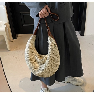 Close-up of beige woven crescent bag with textured crochet and brown leather strap