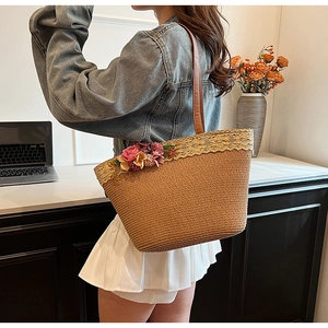 Detail of hand-woven straw tote with golden lace trim and delicate floral accents