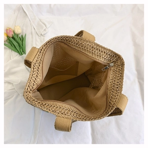 Interior detail of straw tote bag showing fabric lining, pocket and zipper closure