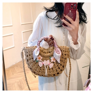 Straw bag featuring pink floral accents and silk scarf handle shown in mirror selfie