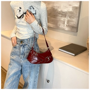 Close-up of deep red glossy leather underarm bag with retro moto style silver buckles
