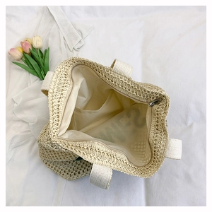 Detail of woven straw tote bag showing beige fabric lining and internal zipper pocket
