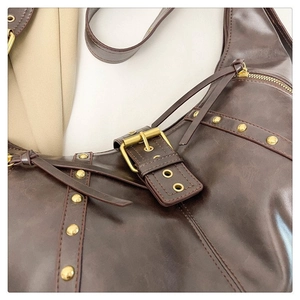 Détail d'un sac à main en cuir marron foncé avec rivets dorés et boucle métallique