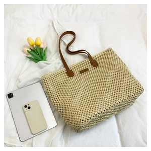 Spacious woven straw tote bag with brown straps and interior space for gadgets