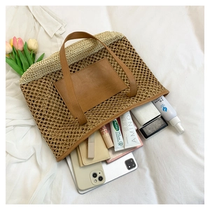 Detail view of woven paper straw beach bag with leather pocket holding daily essentials