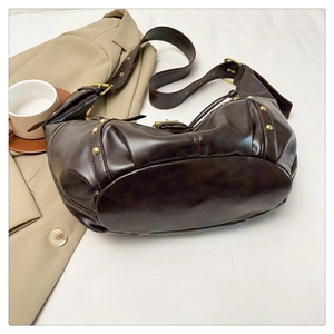 Détail du sac bandoulière marron foncé avec rivets dorés et bandoulière réglable