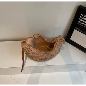 Detail view of the handwoven khaki straw bag showing the brown leather strap and inner pocket