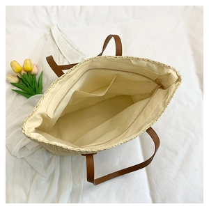 Interior view of straw tote bag showing zipper pocket and spacious beige lining