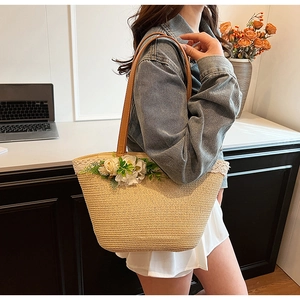 Detailed view of straw tote bag with 3D fabric flowers and brown PU leather shoulder straps