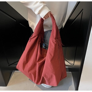 Detalle del bolso tote rojo ladrillo de gran tamaño con cordón lateral y textura plisada