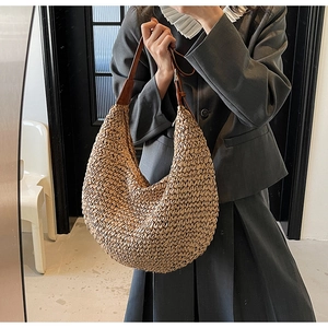 Detail of hand-woven straw hobo shoulder bag with contrasting brown leather handle strap