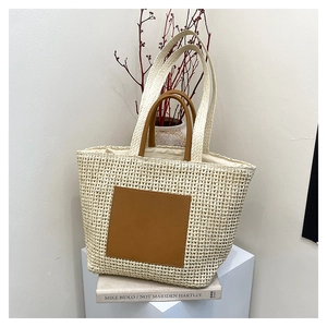 Large beige woven straw tote bag with brown leather handles for summer beach vacations