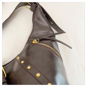 Détail du sac en cuir marron vintage avec rivets dorés et fermeture éclair métallique premium