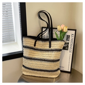 Detailed macro view of woven straw tote bag with black stripes and zipper closure