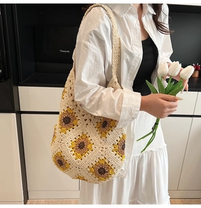 Detail of handmade crochet shoulder bag featuring vibrant sunflower patterns and knit texture