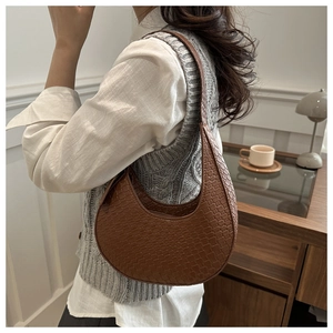 Detail einer braun geflochtenen Halbmond-Hobo-Tasche mit verstellbarem Riemen am Modell