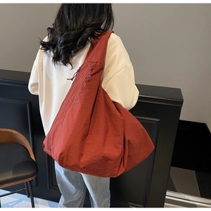 Detalle de la correa ancha y el tejido de nailon texturizado rojo óxido del bolso hobo