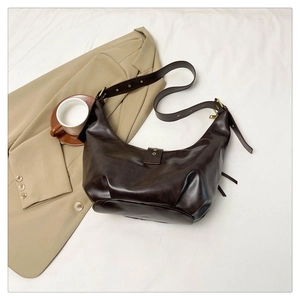 Détail d'un sac demi-lune marron café avec sangle réglable et ferrures dorées