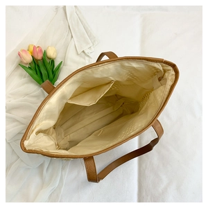 Top view of brown leather tote interior with beige fabric lining and a secure zipper pocket