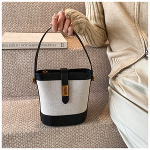 Détail du sac seau en toile texturée avec garniture en cuir noir et fermoir doré chic