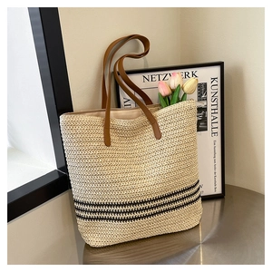 Close-up of beige woven tote bag with black stripes and brown leather straps