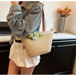Close-up of straw tote bag featuring delicate lace trim and 3D floral decorations