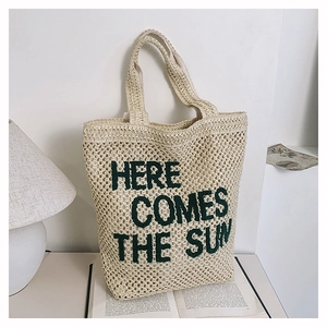 Minimalist beige woven tote bag with green Here Comes The Sun embroidery for beach